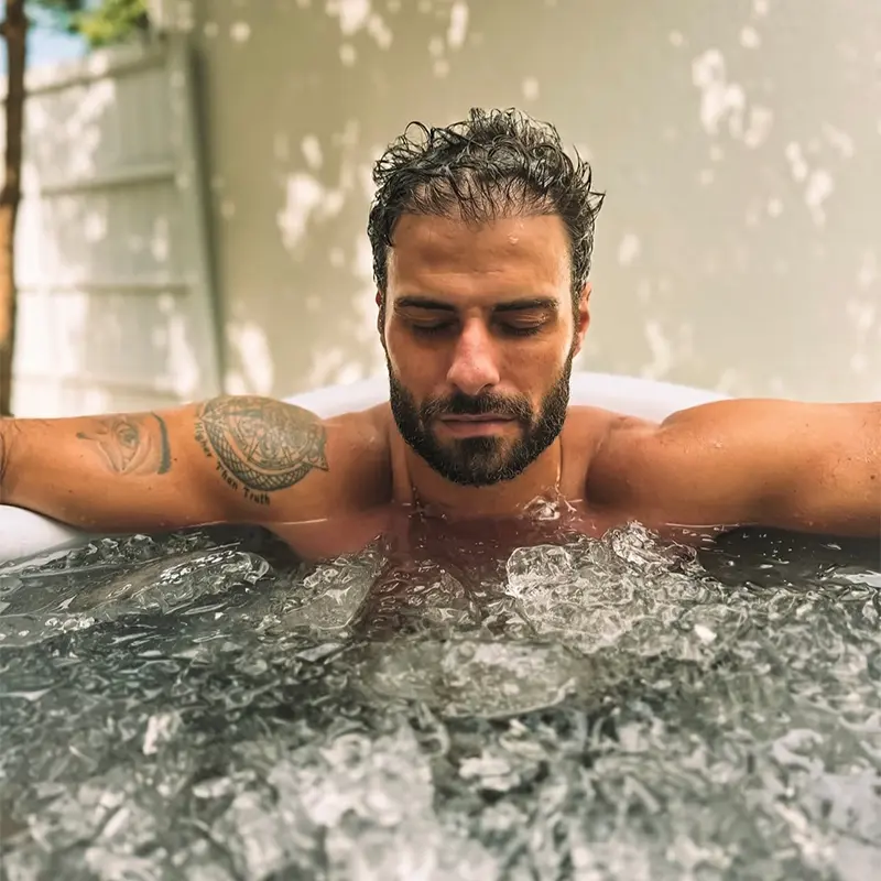 Homem em banheira de gelo com água até o tronco, ilustrando quanto tempo devo ficar na banheira de gelo durante a recuperação