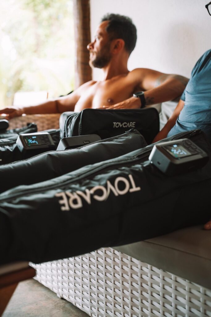 Pessoas usando botas pneumáticas de compressão Tovcare durante uma sessão de recuperação, sentadas em um ambiente relaxado.