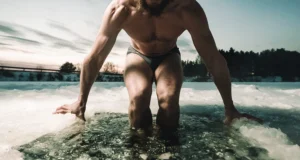 Homem entrando em água gelada durante banho de gelo para recuperação física após treino